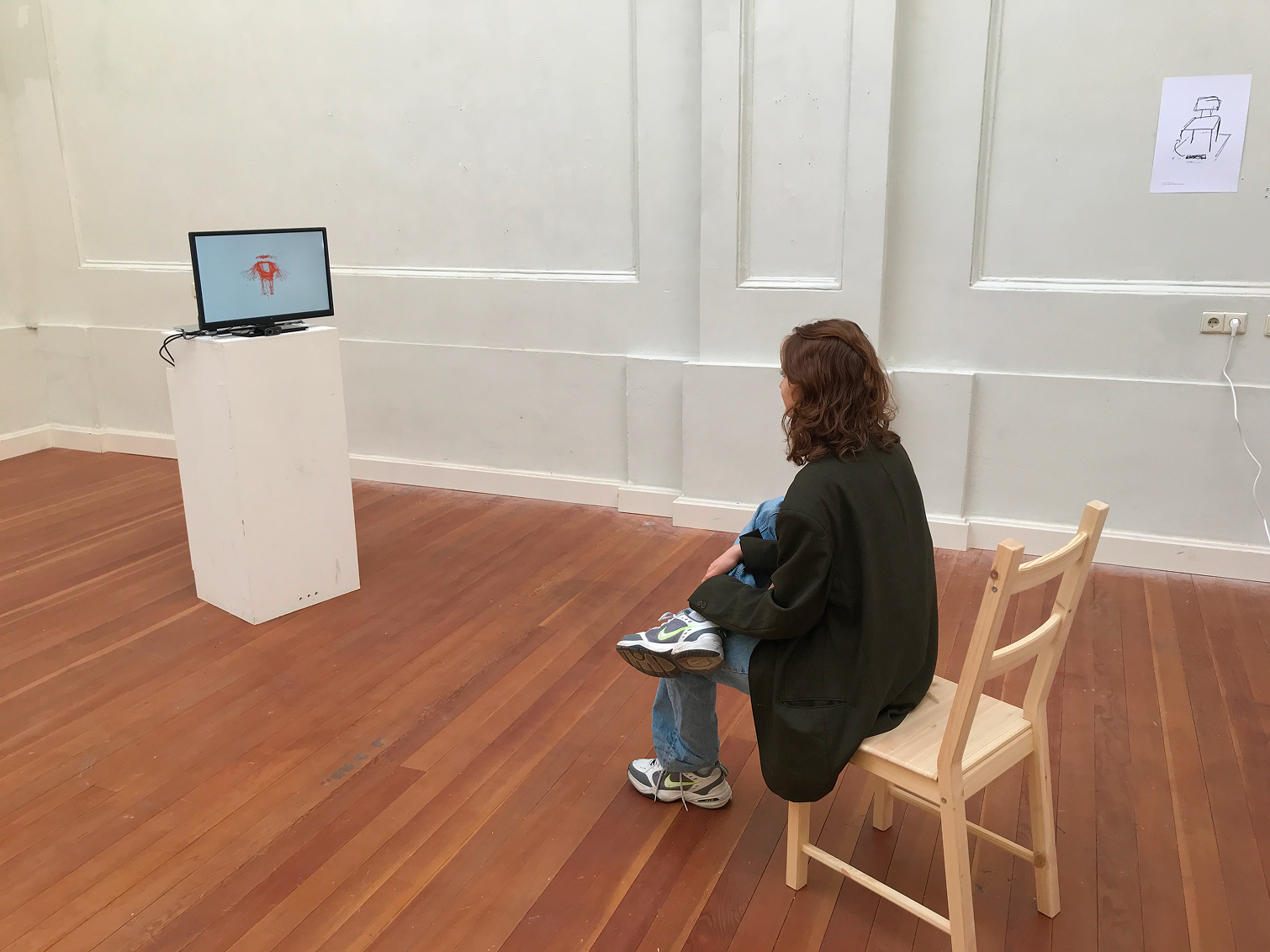 Wooden chair facing a tv screen with a webcam that shows a white canvas with multiple abstracted skeletons layered over each other