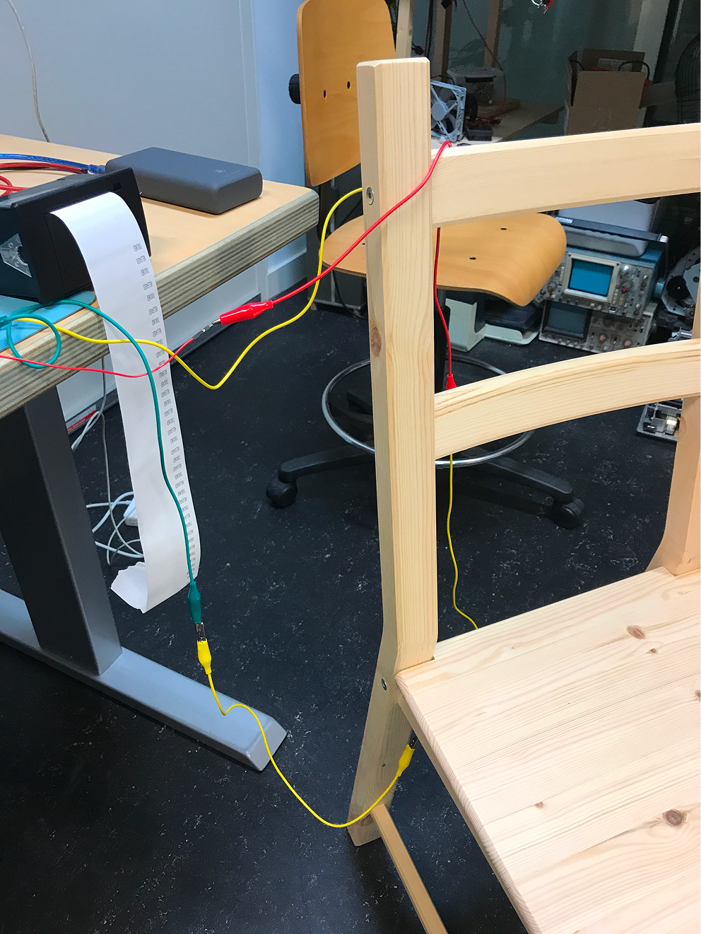 A wooden chair upside down on a table with aluminum foil glued to the bottom of the chair