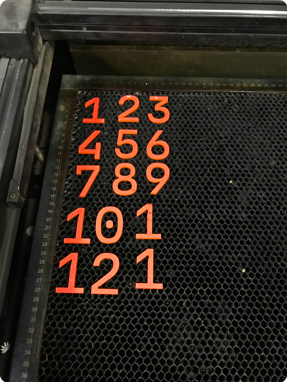 Numbers cut out of plastic lying inside of a laser cutter