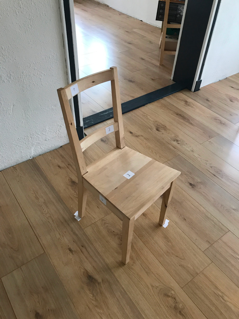 A wooden chair with stickers with numbers written on them glued to the parts of the chair